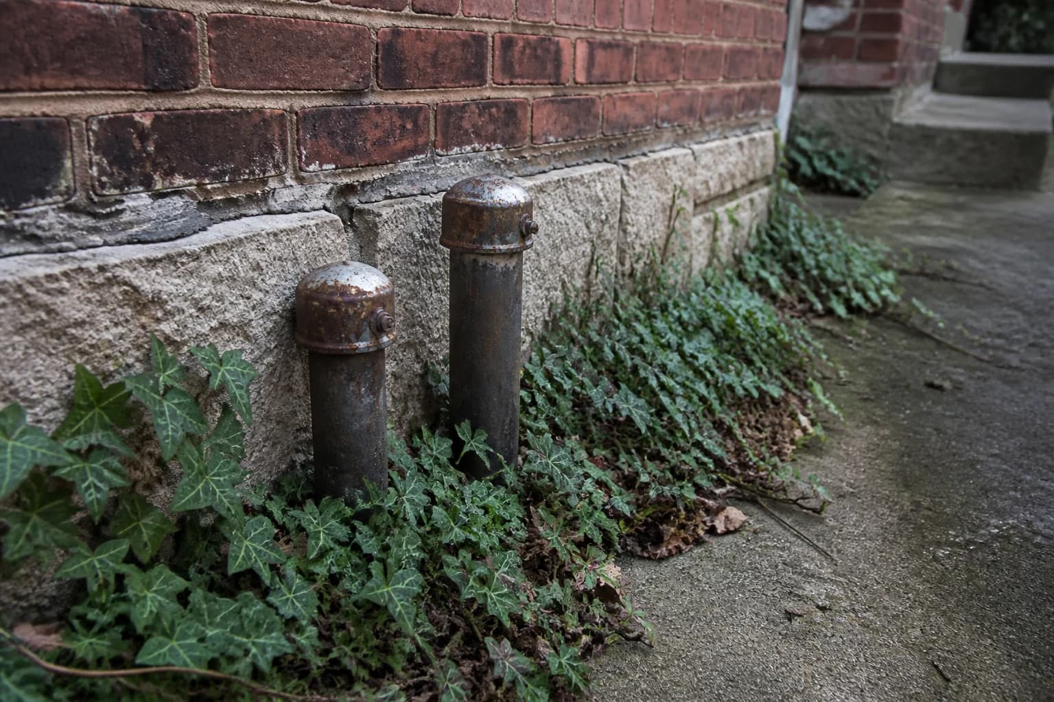 Old heating-oil fill and vent pipes beside a Baltimore brick rowhouse